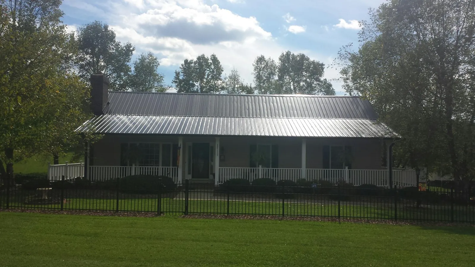 Gray metal roof on a brick ranch with a full width front porch — Gutter Guard Installation work by our crew in Allenton